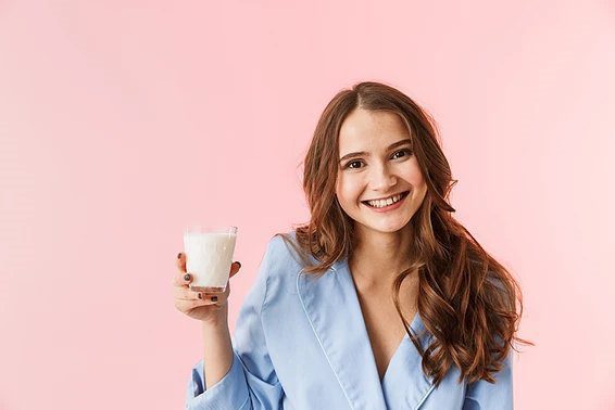 A smiling woman holding a glass of milk